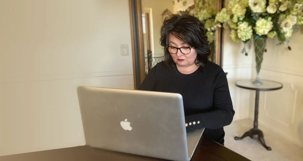 Stephanie Mason, creator of ING energy system, working at laptop with warm smile