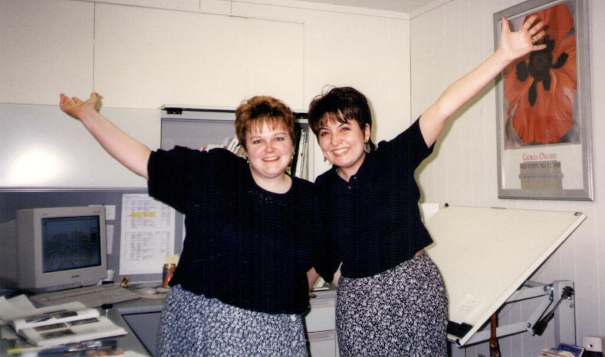 Two coworkers celebrating together in office showing positive workplace ING energy in relationship